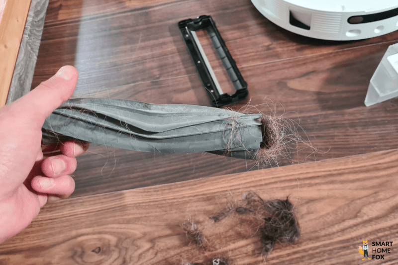 Haare werden aus der Bürste eines Saugroboters entfernt.